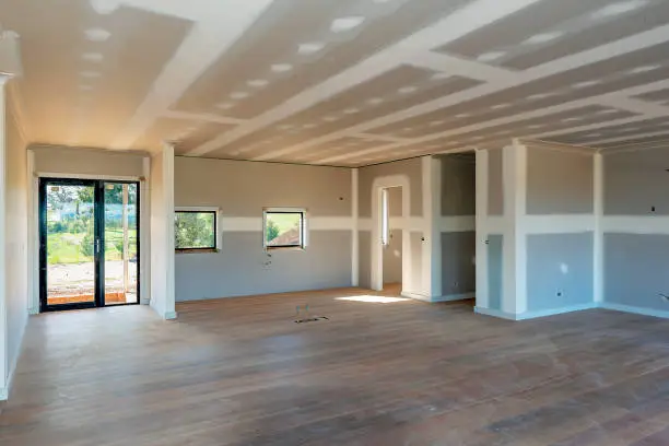 Interior view of a commercial construction project with drywall installation and unfinished flooring.